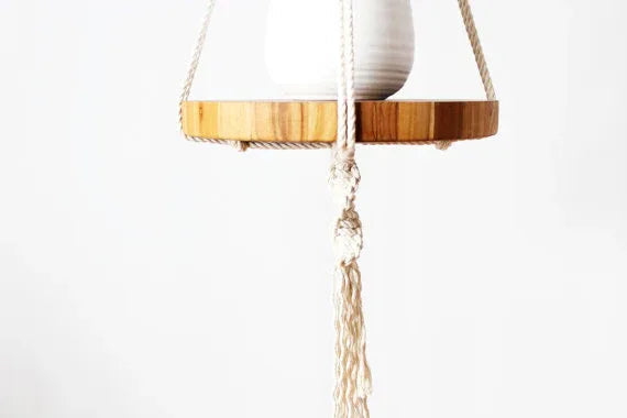 Close-up view of detailed knots and woven pattern of macrame plant hanger with wooden tray below pot.