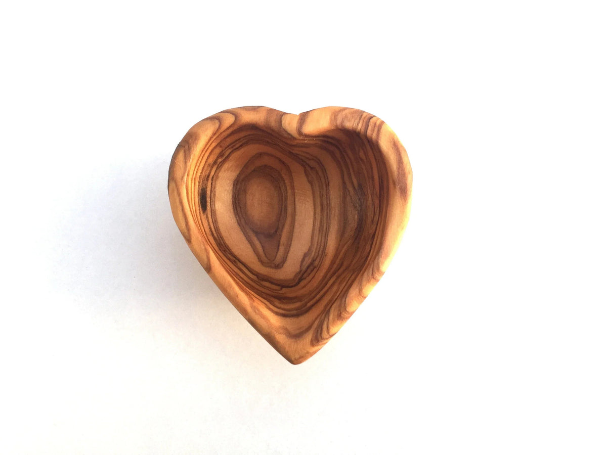 Heart-shaped mini dish holding small gold jewelry on a white surface.