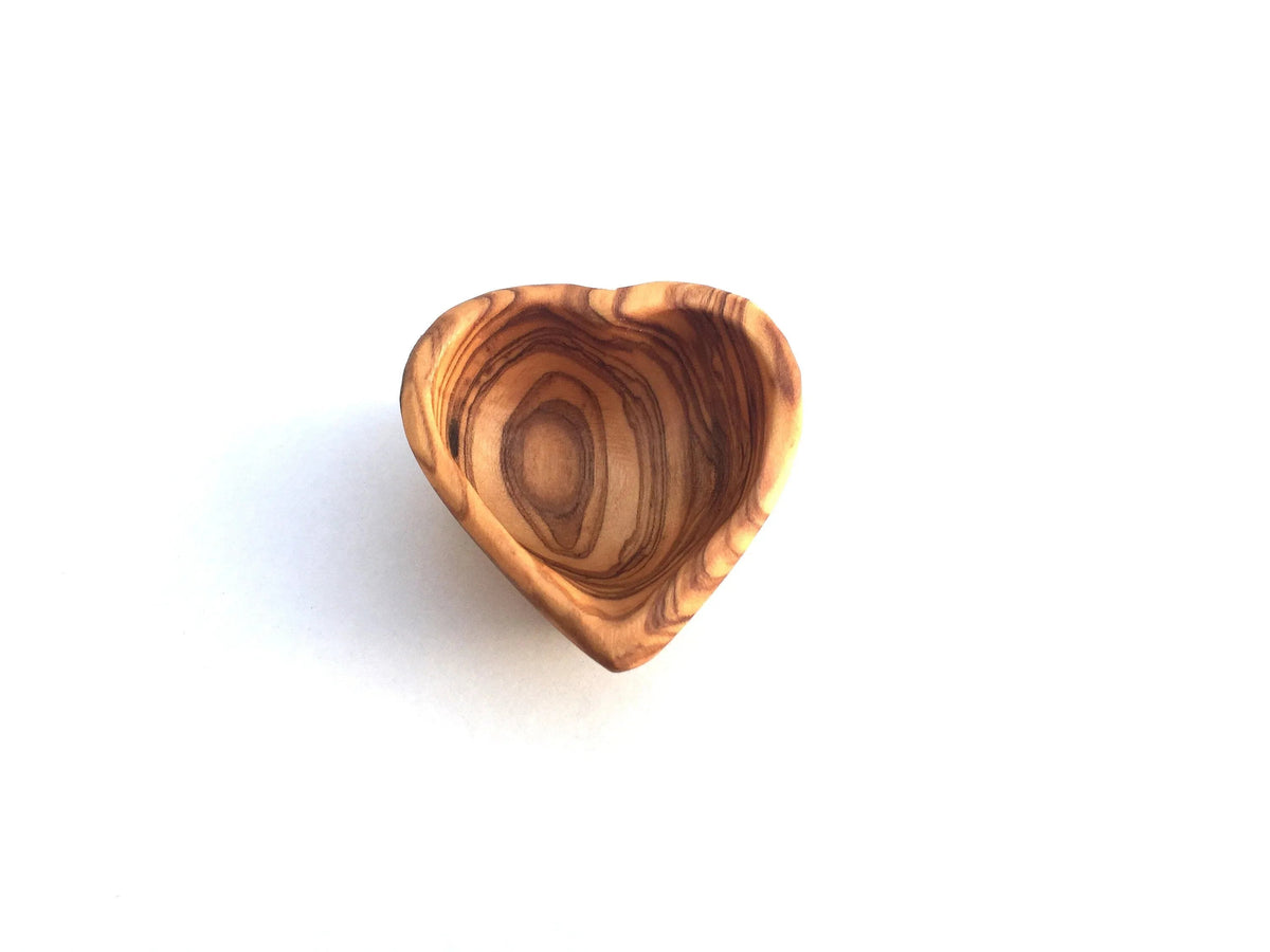 Close-up of heart-shaped dish with delicate rings inside on soft fabric.