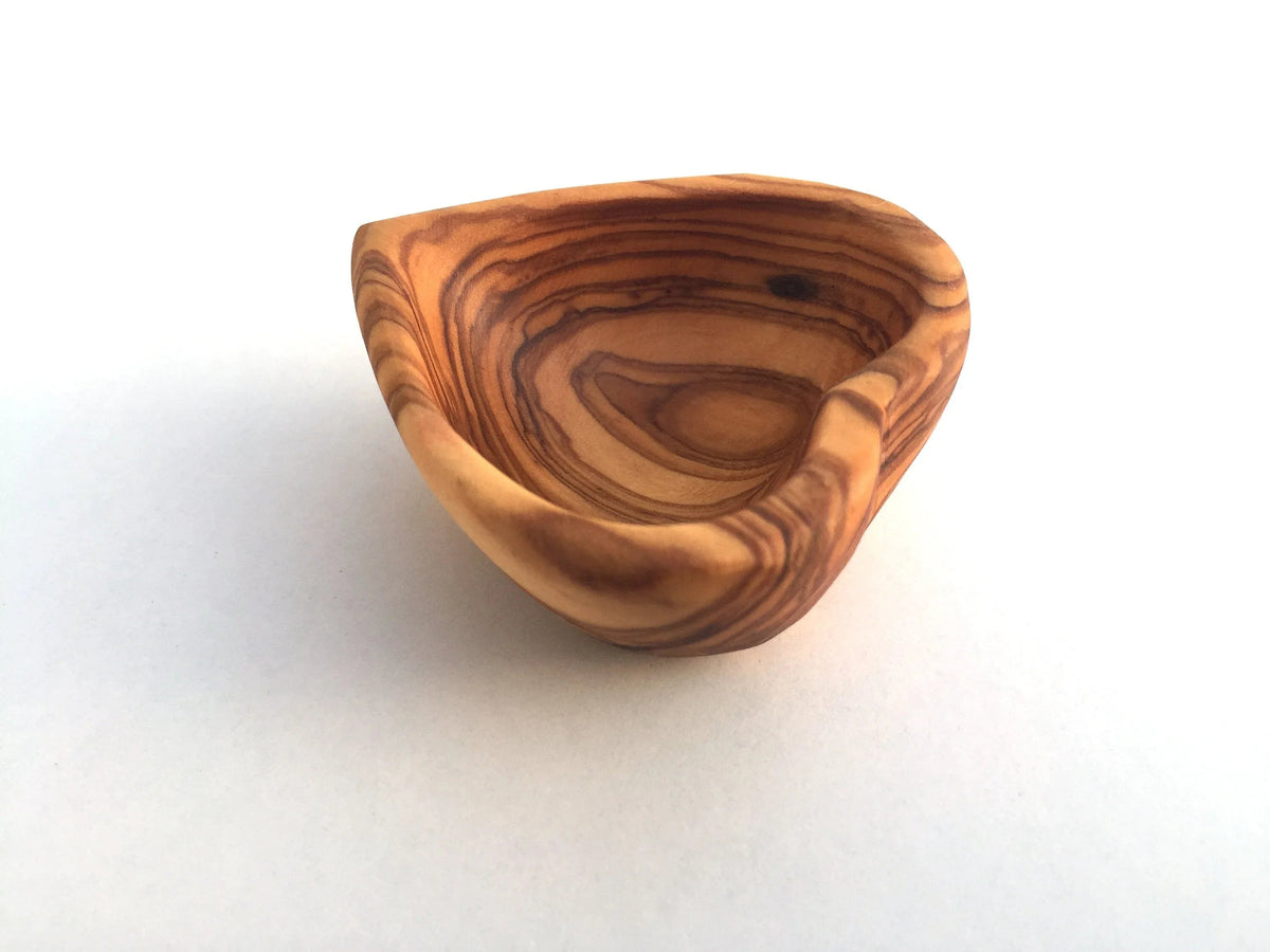 Mini heart-shaped dish with various jewelry pieces inside on white background.