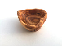 Mini heart-shaped dish with various jewelry pieces inside on white background.