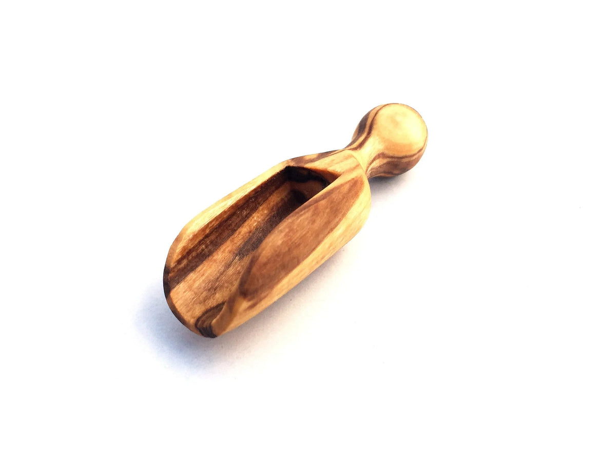 Close-up of a mini salt scoop from the set showing its small size and wooden handle.
