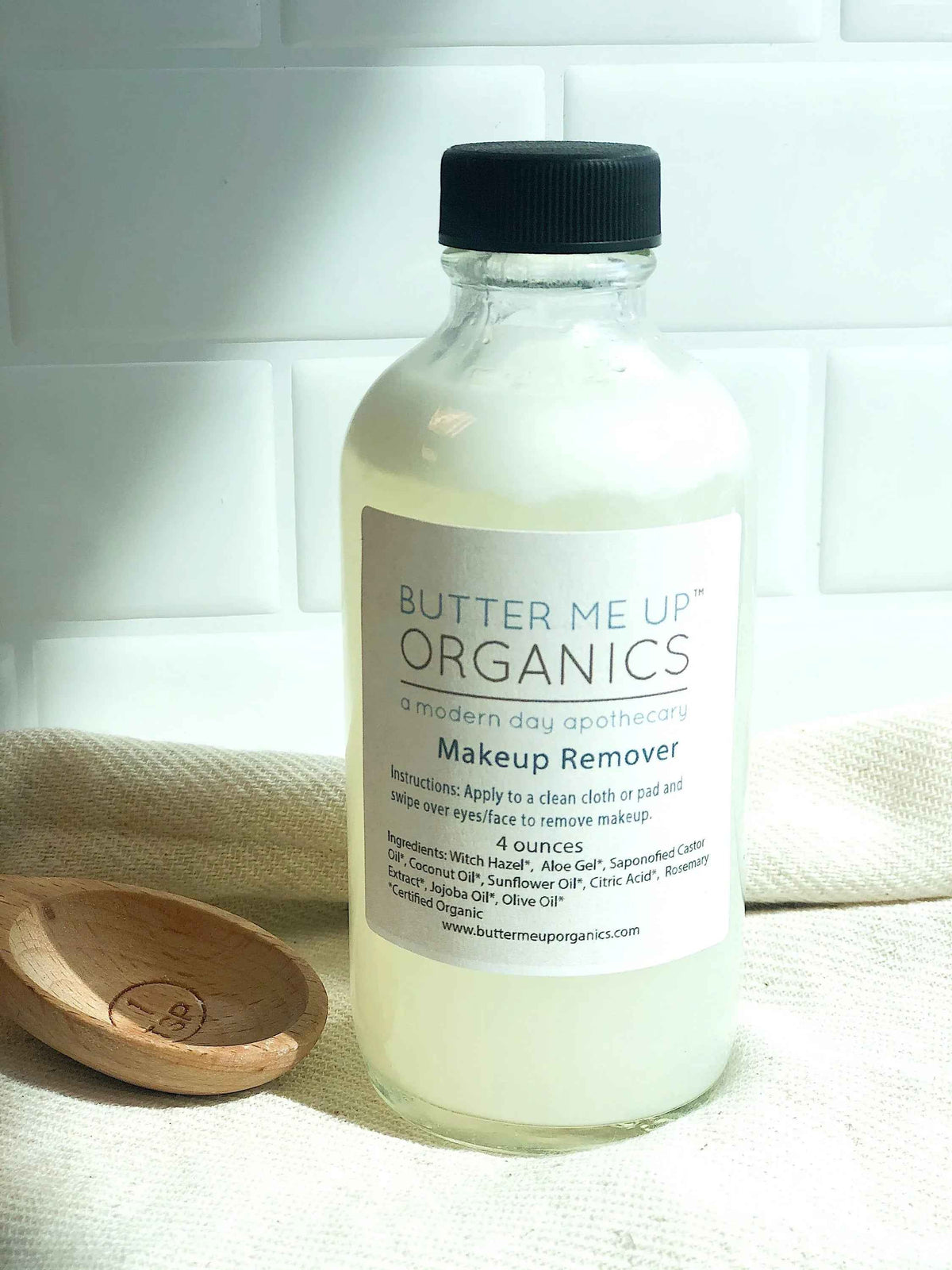 Close-up of liquid organic makeup remover with clear, light yellow color in glass bottle.