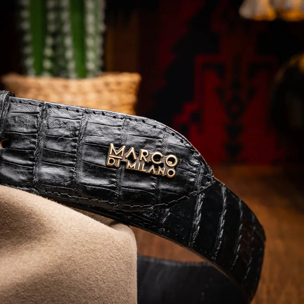 Man adjusting black caiman belt while wearing denim and casual shirt