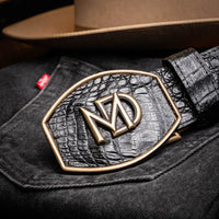 Black caiman skin belt styled with dark denim in an outdoor setting