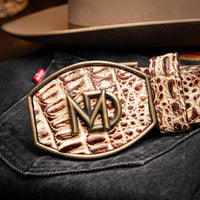 Close-up lifestyle view of belt featuring natural caiman scales and antique brass buckle on wearer.