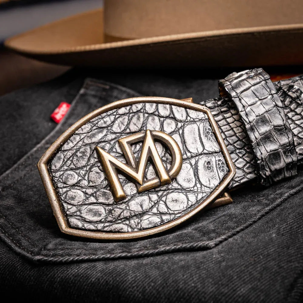 Individual adjusting gray caiman crocodile belt over blue denim pants.