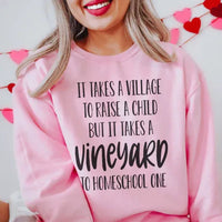 Light pink sweatshirt featuring 'It Takes A Vineyard To Homeschool A Child' text in red and white typography.