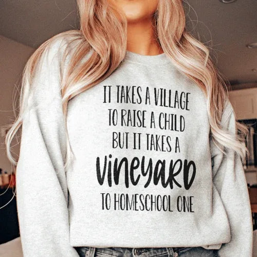 Sport grey sweatshirt shown from front angle with 'It Takes A Vineyard To Homeschool A Child' phrase in stylized font.