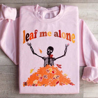 Light pink sweatshirt featuring a bright orange and yellow autumn leaf graphic and Leaf Me Alone Fall text