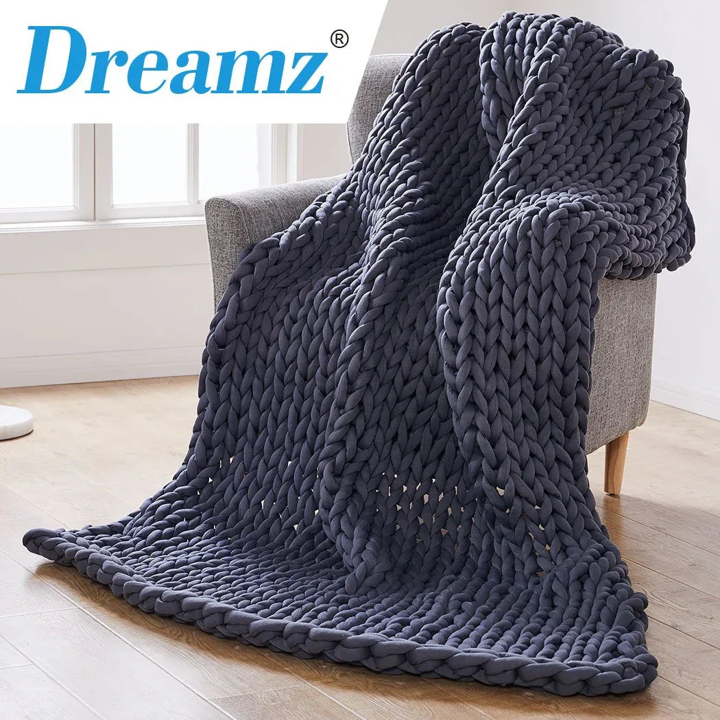 Lifestyle image of a cozy living room with chunky knit weighted blanket draped over a sofa.