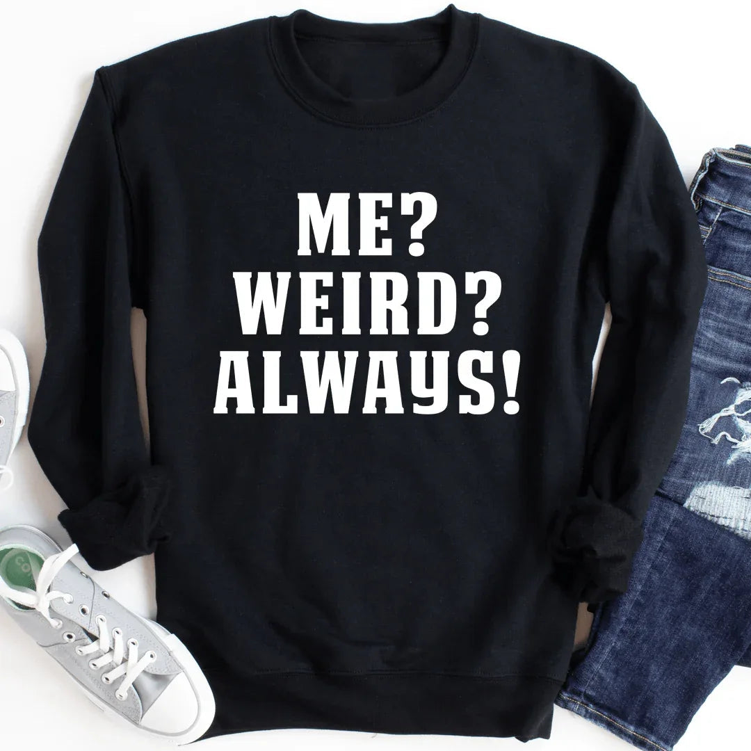 Black sweatshirt with white text 'Me? Weird? Always!' on front, cozy fleece fabric with banded cuffs.