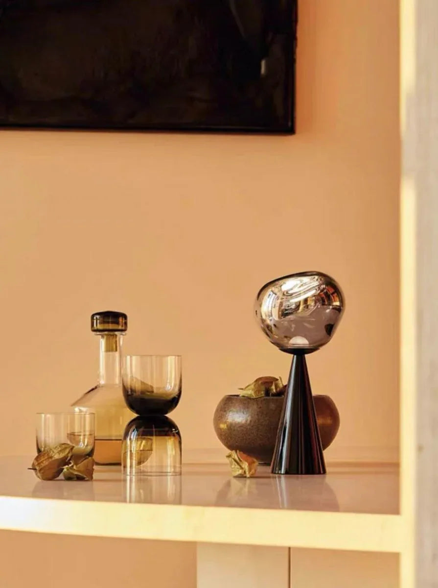 White modern Nordic table lamp glowing brightly on a bedside table with books and decor.