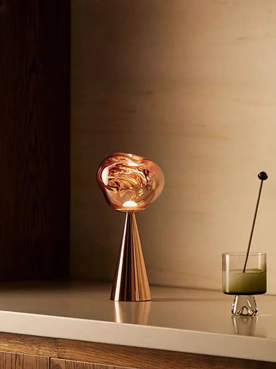 Dimmed LED table lamp casting a soothing warm light beside a bed in a minimalist room.