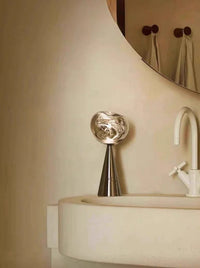 Hand holding a compact portable table lamp with dimmable warm LED light in a bedroom.