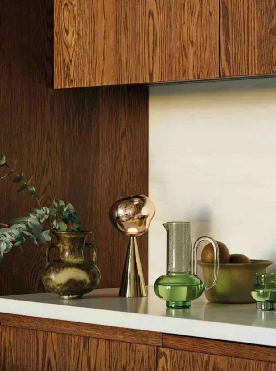 Portable rechargeable table lamp with a soft glowing light on a tan bedside surface.