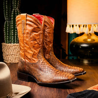 Person wearing Missouri python skin cowboy boots with jeans in rustic outdoor setting.