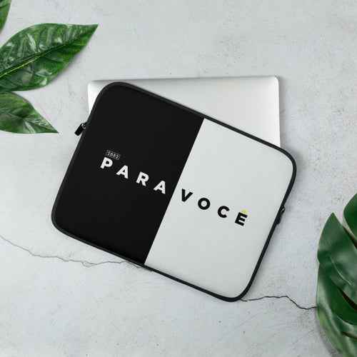 Modern black and white color block laptop sleeve placed on a desk next to a notebook and pen.