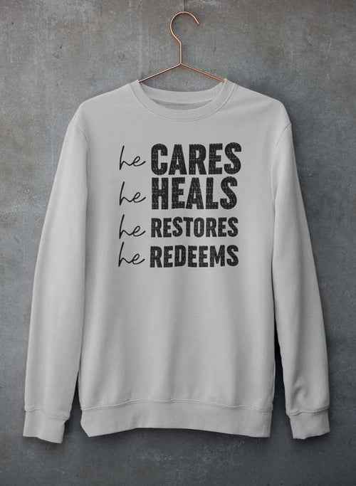 Close-up of gray crewneck sweatshirt with printed religious phrase on front, hanging on hanger.