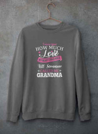 Close-up of gray crewneck sweatshirt with printed heartfelt quote hanging against concrete background.