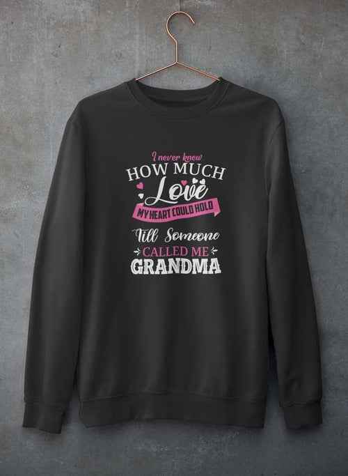 Gray crewneck sweatshirt featuring a loving quote, showcased hanging on a textured concrete wall.