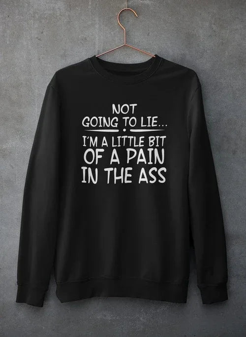 Close-up of light gray crewneck sweatshirt with text print hanging against rough concrete wall.