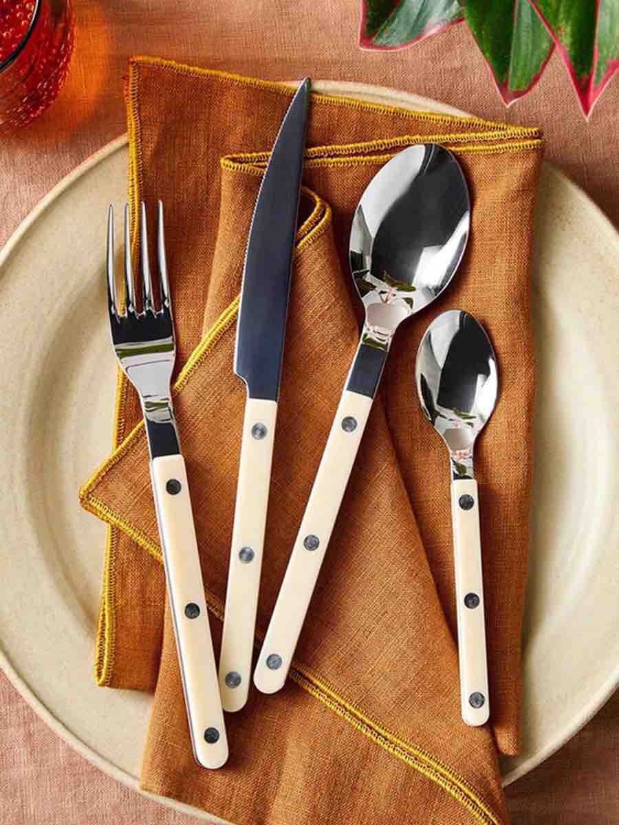 Elegant modern Nordic flatware set with ivory handles, including forks, knives, and spoons displayed on a wooden surface.