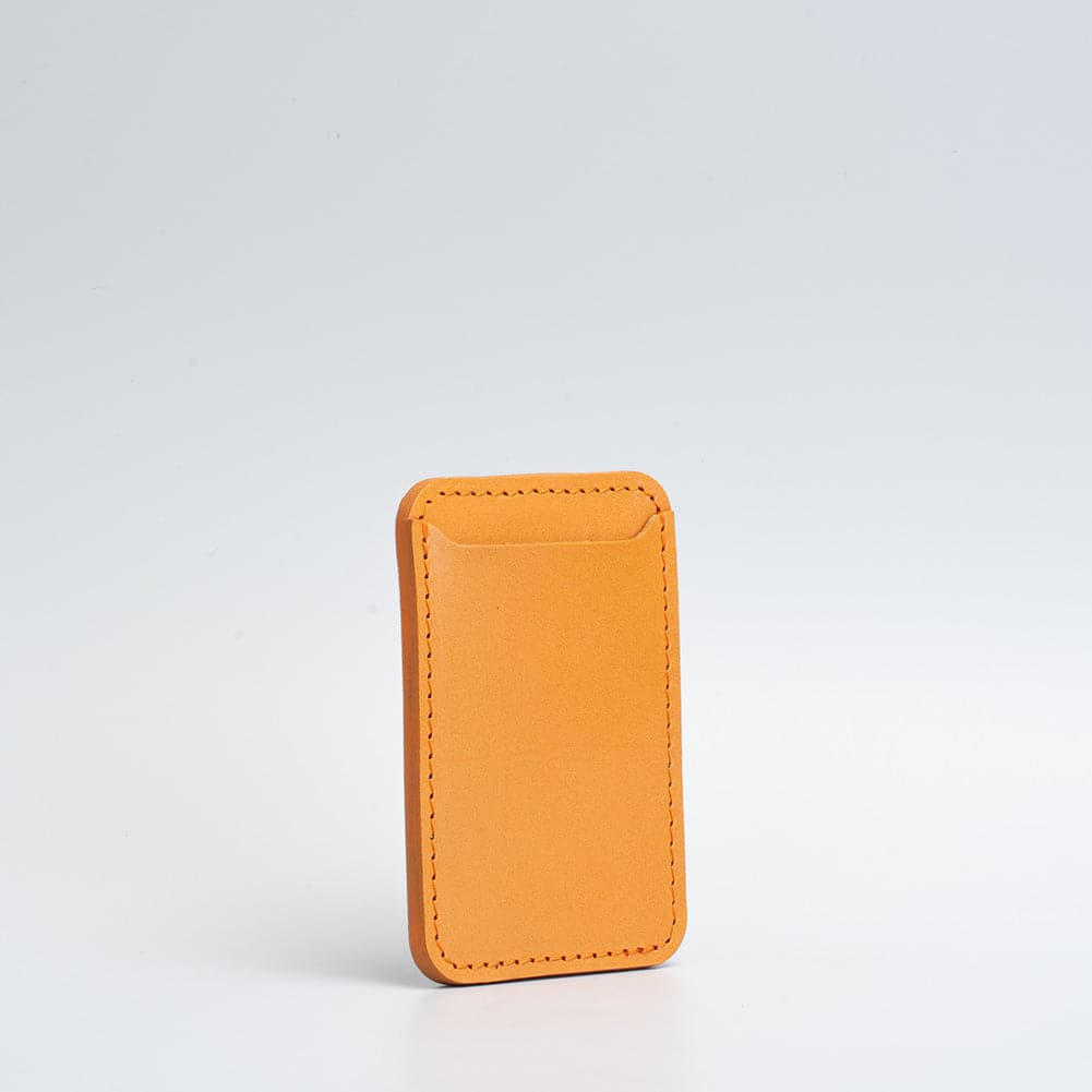 Orange leather MagSafe wallet for iPhone shown against a white background.