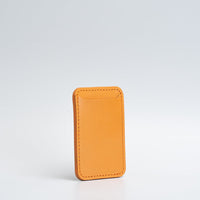 Orange leather MagSafe wallet for iPhone shown against a white background.