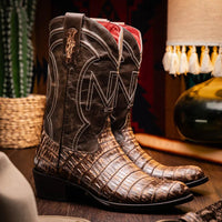 Lifestyle image of Phoenix Stone Brown cowboy boot worn with jeans outdoors on stone surface.