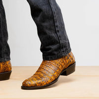 Casual outdoor scene with man wearing mustard brown caiman leather cowboy boots on gravel.