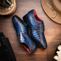 Man standing on pavement wearing Ragusa navy caiman derby shoes with rolled-up navy pants.