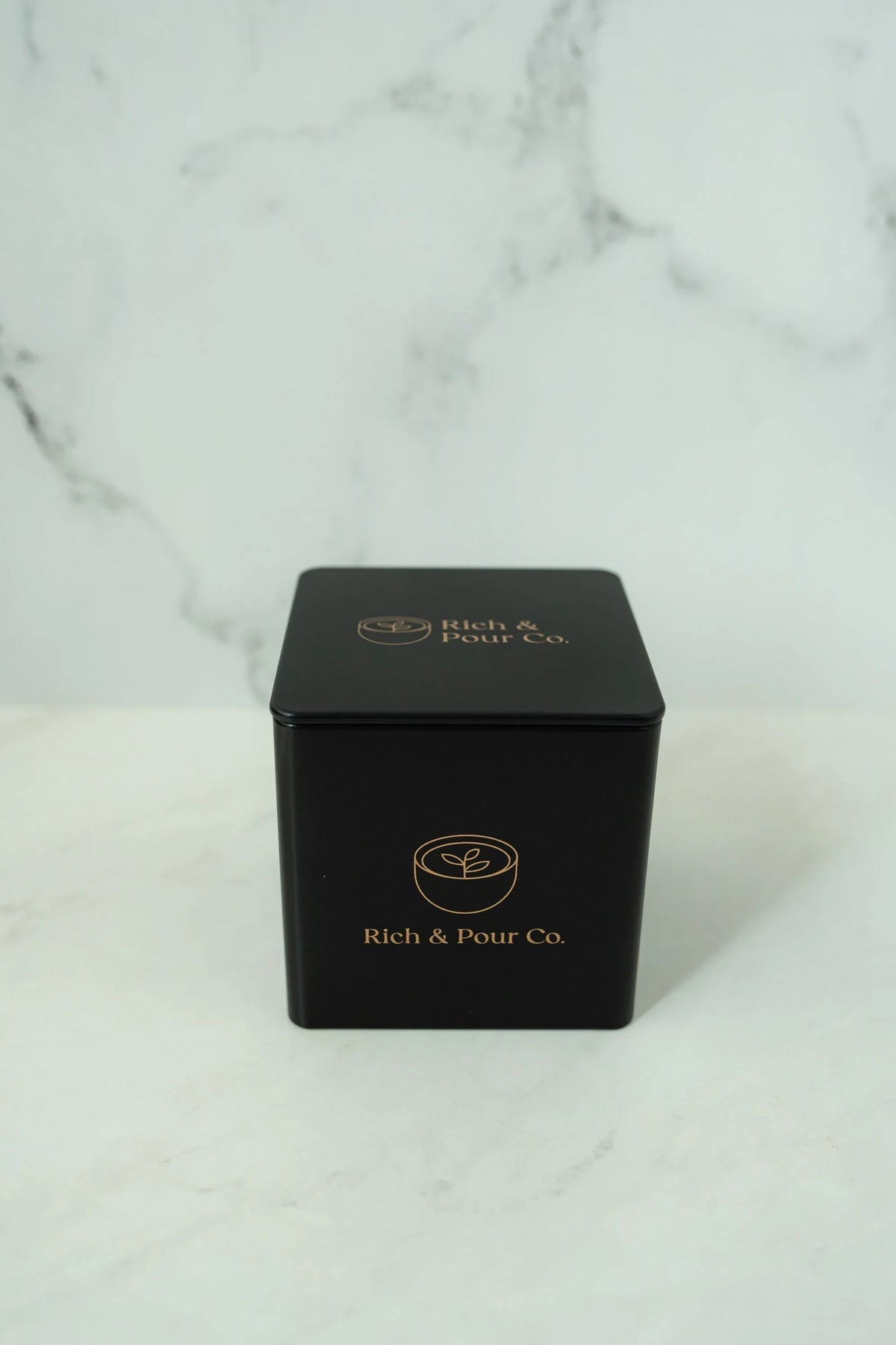 Overhead shot of three reusable tea storage tins arranged on a light-colored background.