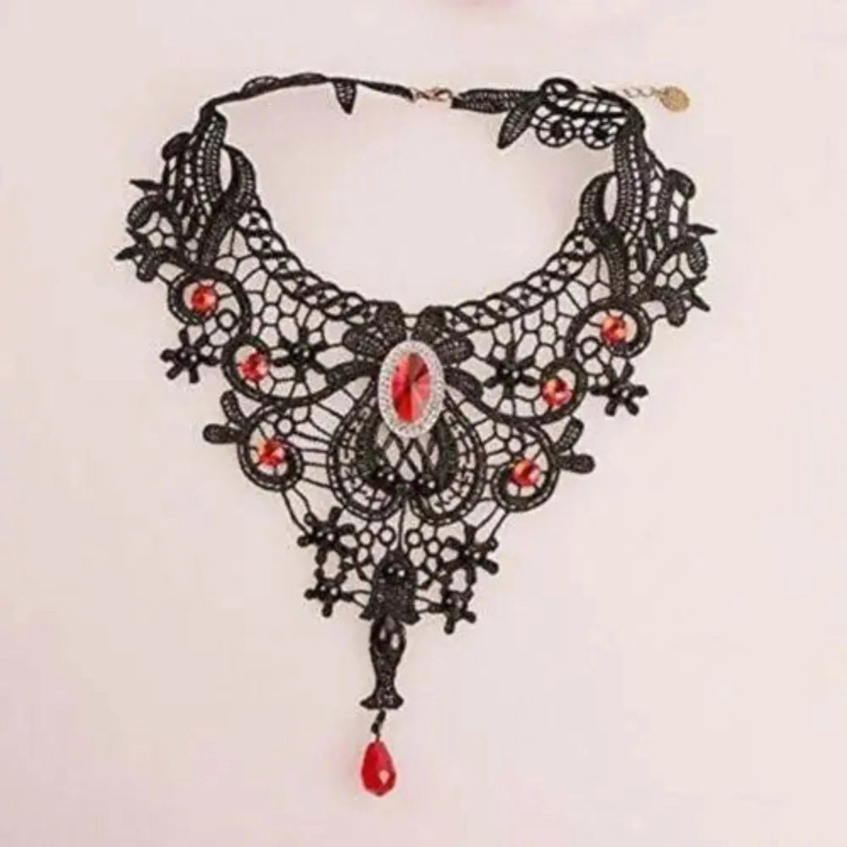 Model looks downward wearing black lace clavicular chain necklace and dark lipstick.