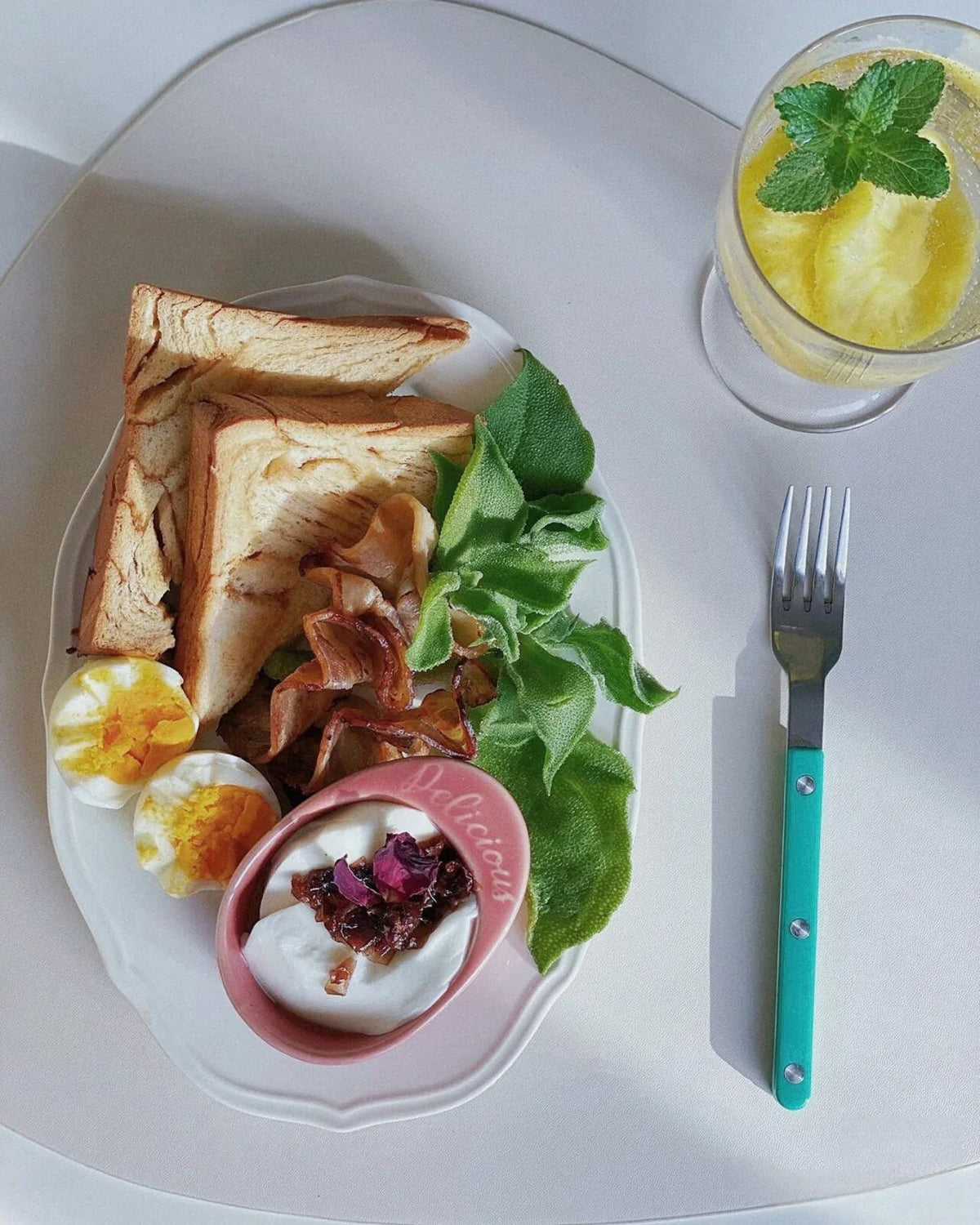 Set of modern turquoise flatware pieces with rivet details placed on a wooden table.
