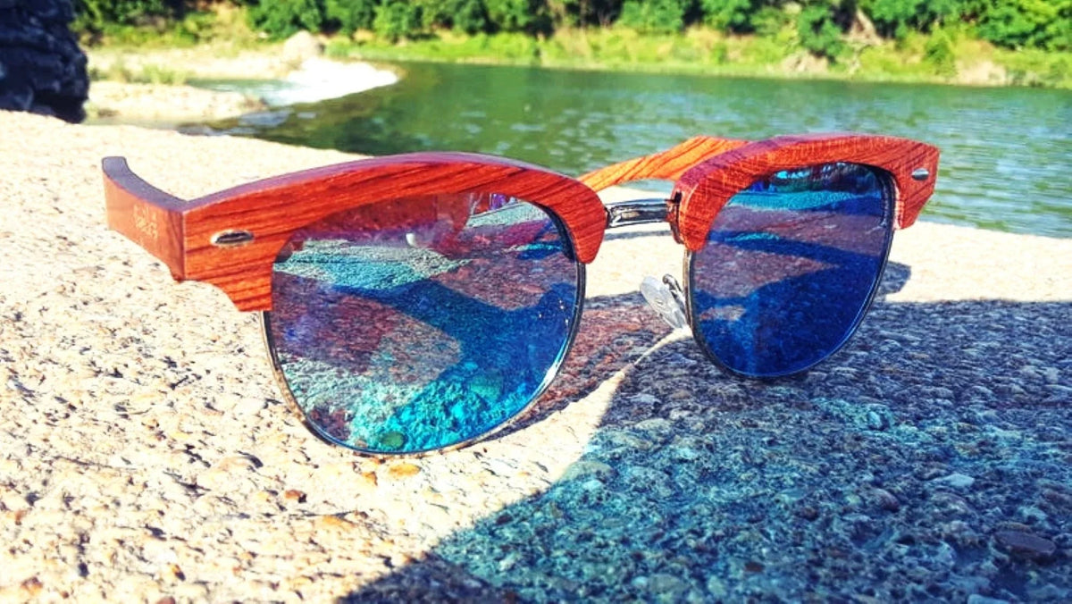 Top view of handcrafted sandalwood sunglasses with blue polarized lenses showing wood grain detail.