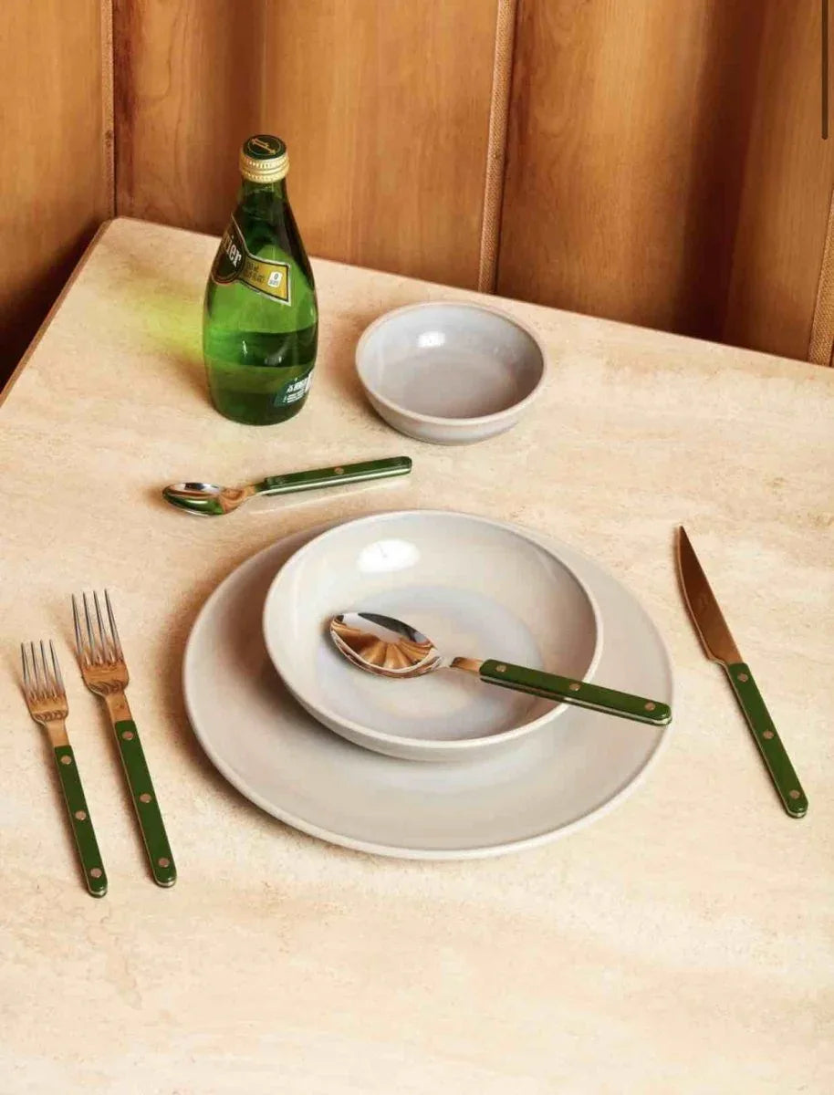 Set of 10 sleek French dopamine cutlery pieces laid out on a dark surface with a bistro style.