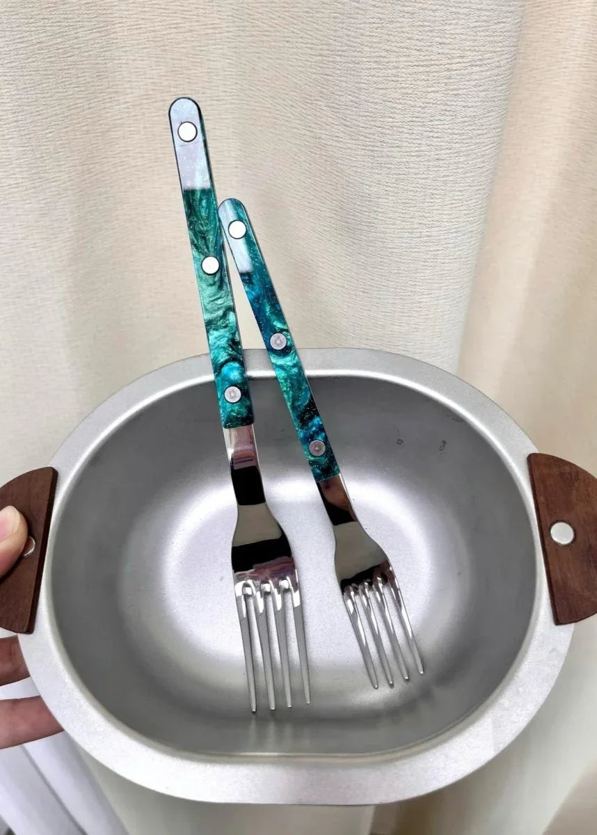 Modern elegant terra flatware pieces lying side by side on dark stone surface