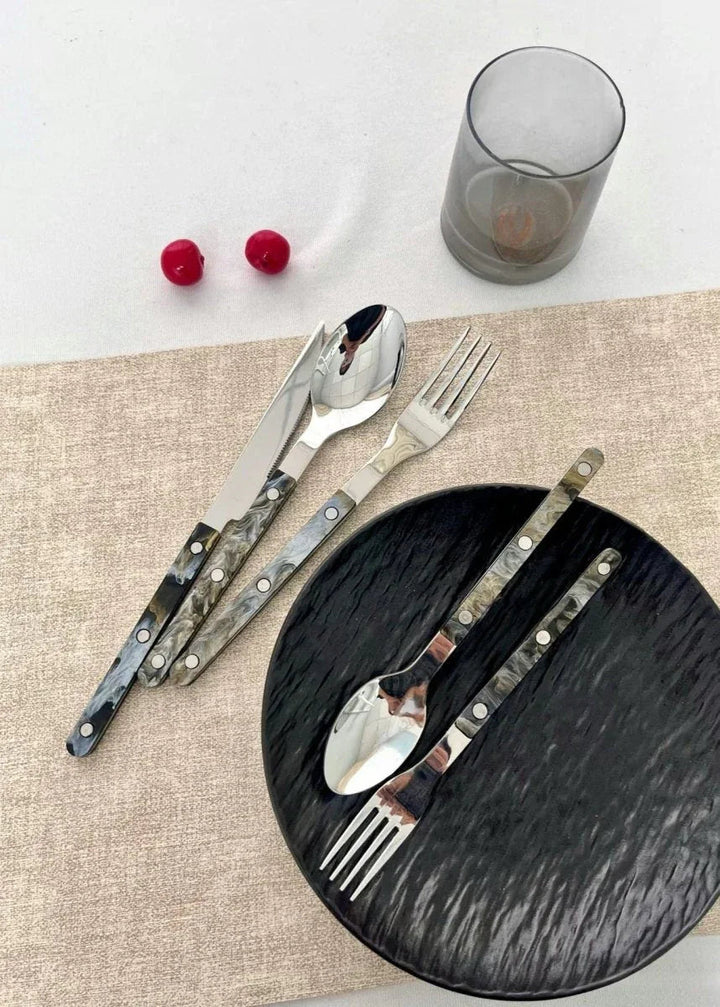 Set of 10 sleek modern terra flatware pieces arranged on dark textured surface