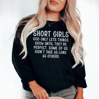Black sweatshirt with text 'Short Girls God Only Lets Things Grow Until They're Perfect' in white font