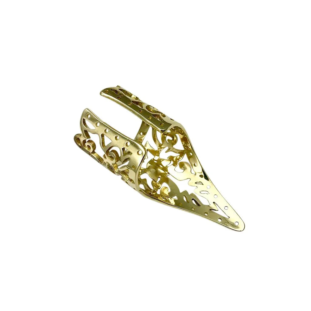 Side angle of a handcrafted brass Khmer ring resting on textured stone surface