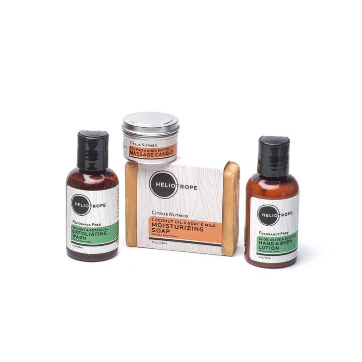 Small basket holding travel-sized body lotion, shower gel, goat's milk soap, and a mini massage candle from the Heliotrope