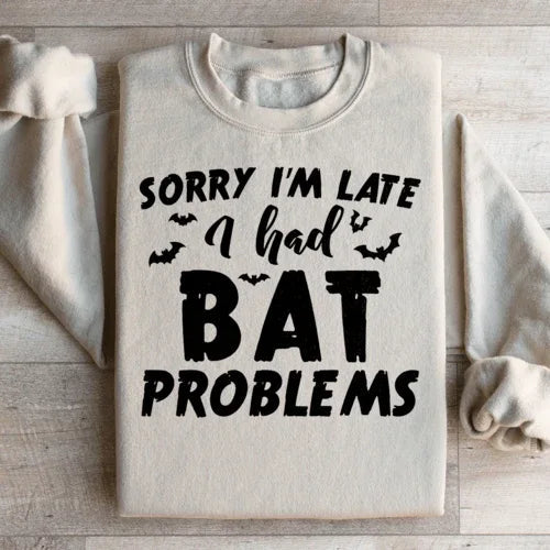 Sand-colored sweatshirt with Sorry I'm Late I Had Bat Problems text in white on front.