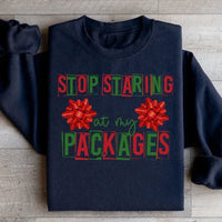 Black sweatshirt featuring the phrase 'Stop Staring At My Packages' on front with ribbed cuffs.