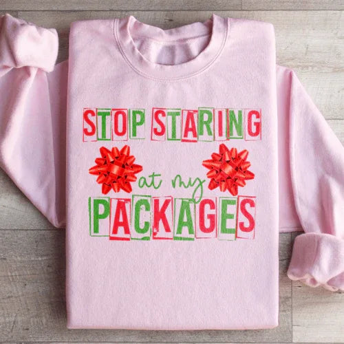 Light pink sweatshirt with 'Stop Staring At My Packages' printed in white font on front.