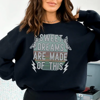 Close-up of black Sweet Dreams sweatshirt showing detailed peachy orange and white graphic design.