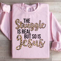 Light pink sweatshirt with large white text saying 'The Struggle Is Real But So Is Jesus'.