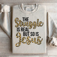 Sand-colored sweatshirt featuring bold white text stating 'The Struggle Is Real But So Is Jesus'.