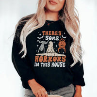 Close-up of black sweatshirt showing white bold text 'There's Some Horrors In This House'.