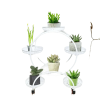 Black metal circular six-tier plant stand showcasing green plants with varied leaf shapes and sizes.